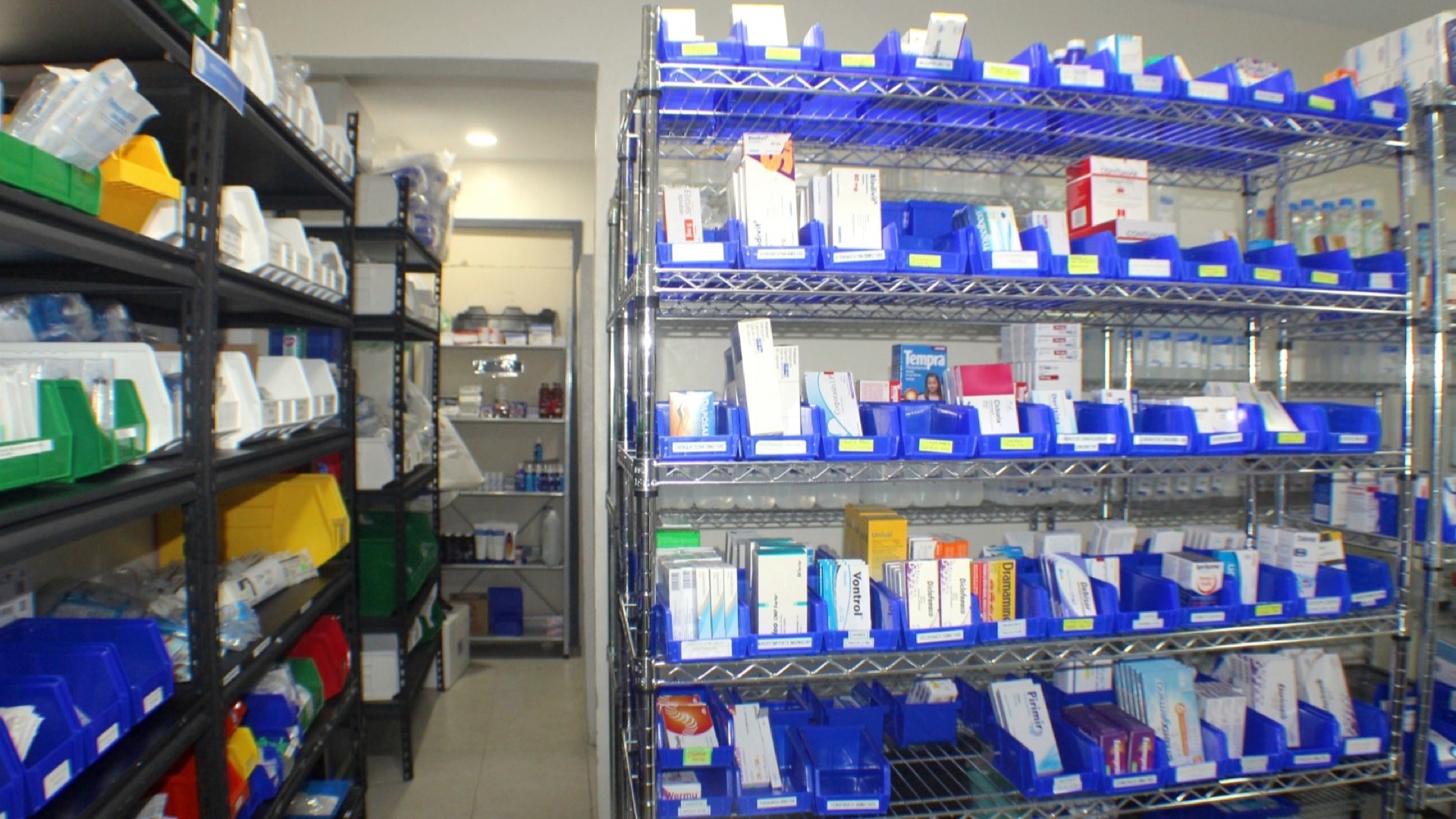 El almacén de la farmacia hospitalaria: estanterías metálicas de cajetines rotulados, cada uno con su medicamento, y el pasillo que las separa.