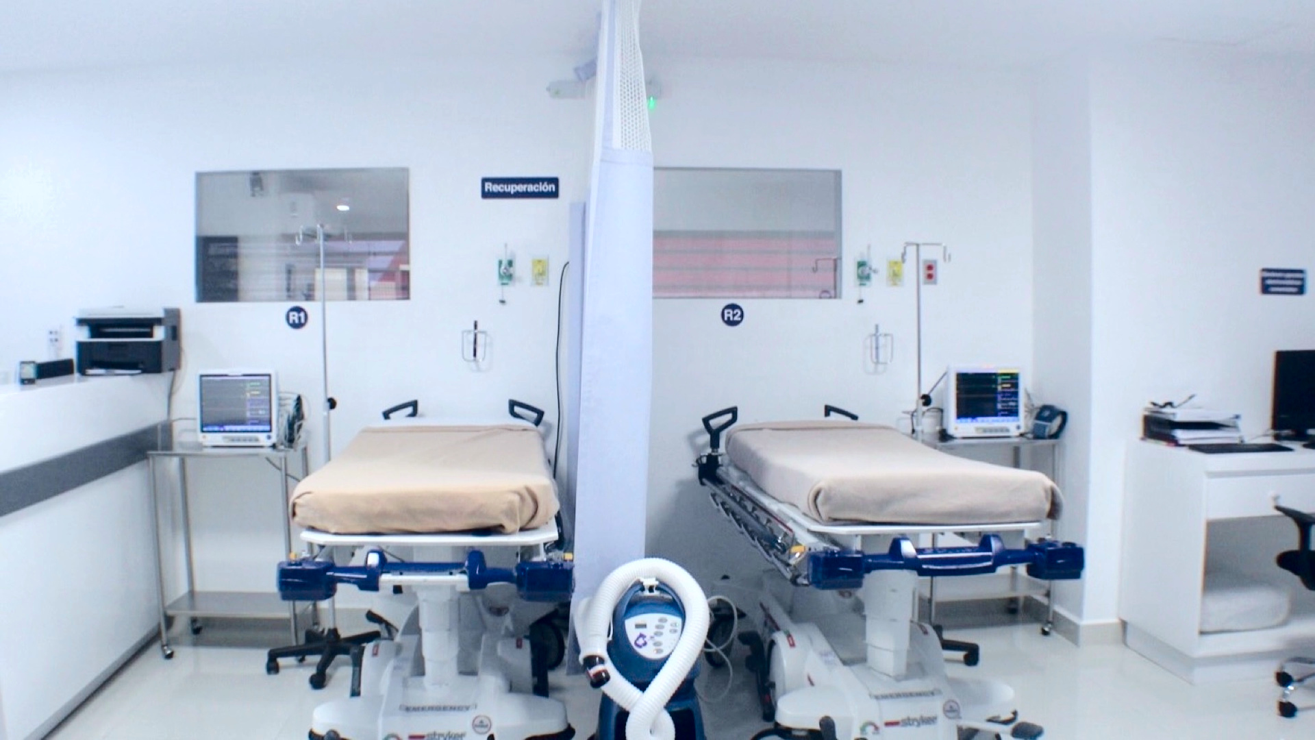 Los dos puestos de recuperación bajo el letrero «Recuperación», rotulados R1 y R2: dos camillas con su monitor, separadas por una cortina.