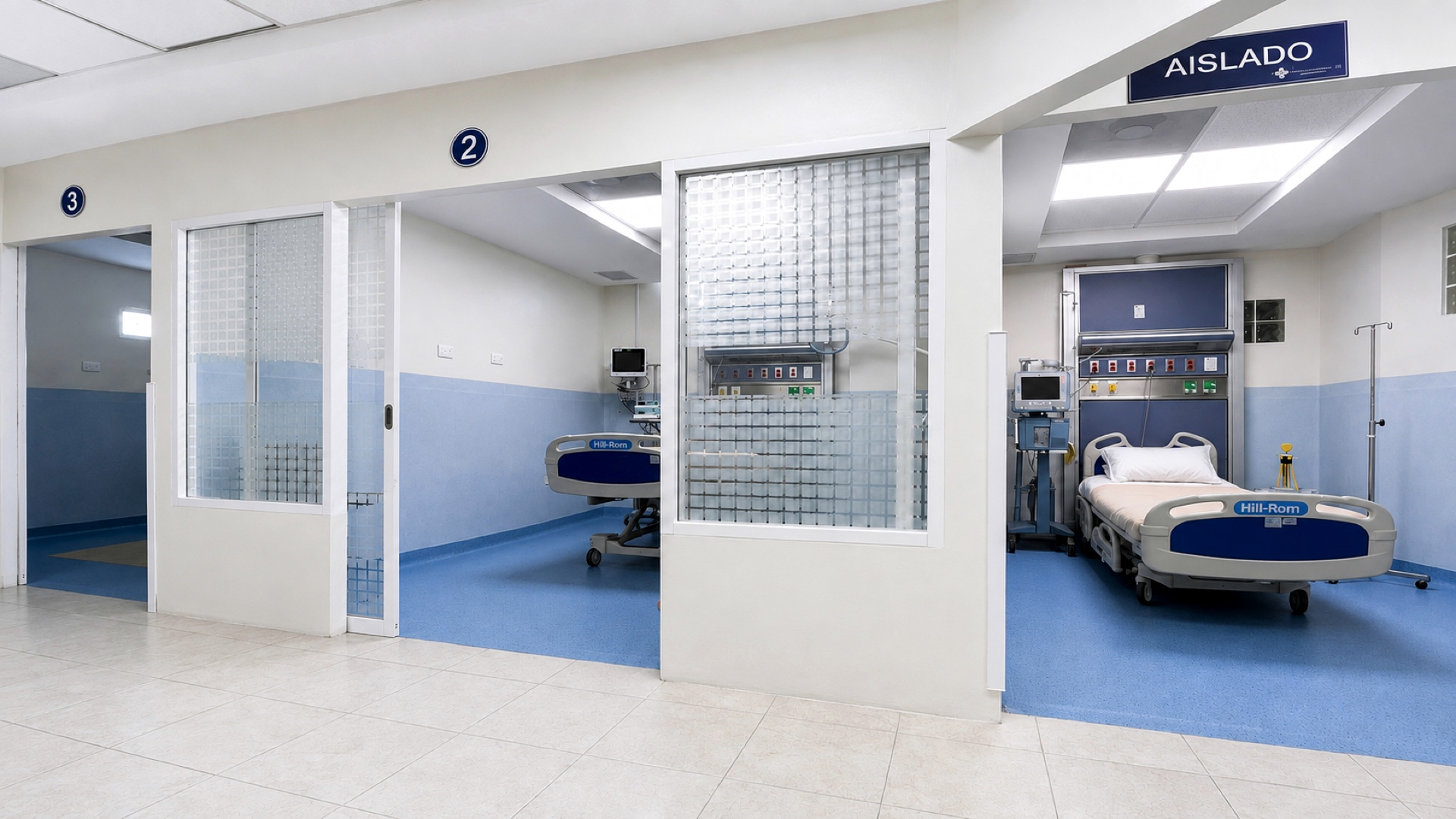 El pasillo de terapia intensiva: los cubículos 3 y 2 tras sus mamparas de pavés y, a la derecha, el puesto rotulado «Aislado», con su cama y el panel de cabecera.